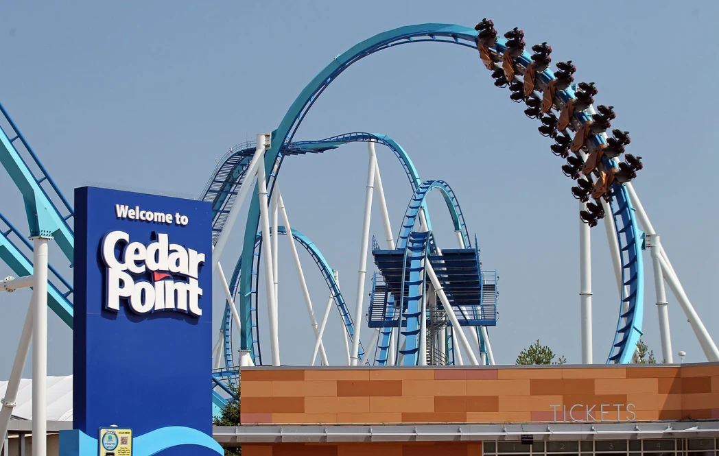 Roller coaster with riders on a loop at Cedar Point. Blue track, clear sky.